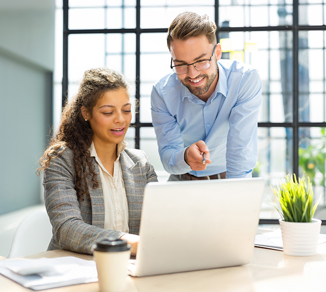 Zwei Mitarbeiterinnen im B&uuml;ro arbeiten gemeinsam am Computer und besprechen Unterlagen.