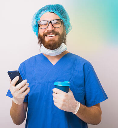 Ein l&auml;chelnder Arzt, der ein Telefon und eine Tasse h&auml;lt.