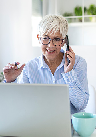 Gesch&auml;ftsfrau telefoniert und arbeitet gleichzeitig am Laptop &ndash; Terminvereinbarung.