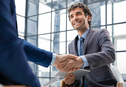 Gesch&auml;ftsmann im Anzug gibt einem Partner die Hand &ndash; erfolgreiches Gesch&auml;ft in Bielefeld.