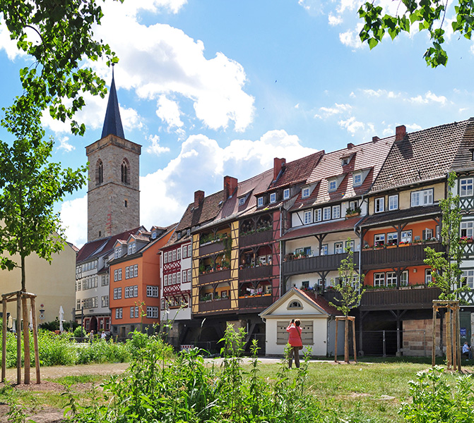 Historische H&auml;user und Fachwerkbauten auf der Kr&auml;merbr&uuml;cke in Erfurt mit blauem Himmel im Hintergrund.