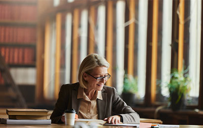 Juristin sitzt am Schreibtisch mit Unterlagen und arbeitet konzentriert in einer modernen B&uuml;roumgebung.