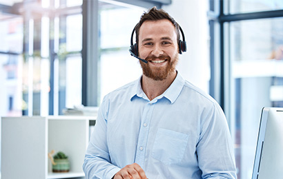 Mitarbeiter mit Headset l&auml;chelt freundlich im modernen B&uuml;ro.