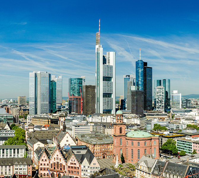 Panoramaaufnahme der Frankfurter Innenstadt mit Bankent&uuml;rmen, historischen Geb&auml;uden und blauem Himmel.