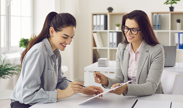 Vertragsunterschift zwischen 2 Frauen an einem Schreibtisch