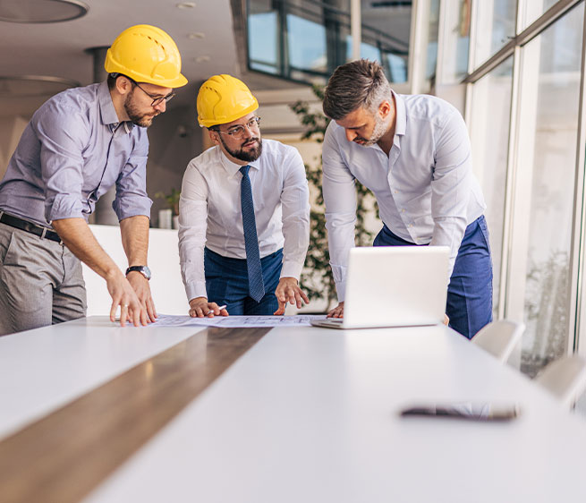 Besprechung von Baupl&auml;nen an einem Schreibtisch