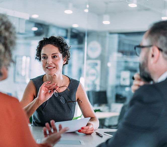 Frau im Business-Outfit im Gespr&auml;ch mit Kollegen &ndash; Beratungsgespr&auml;ch im modernen B&uuml;ro.