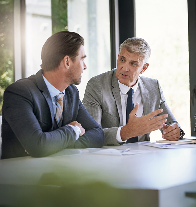 Gespr&auml;chssituation zwischen 2 Herren im B&uuml;ro am Schreibtisch