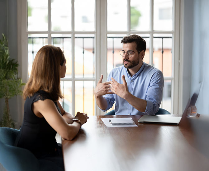 Ein Mann und eine Frau sitzen sich an einem Tisch gegen&uuml;ber und f&uuml;hren ein konzentriertes Gespr&auml;ch.