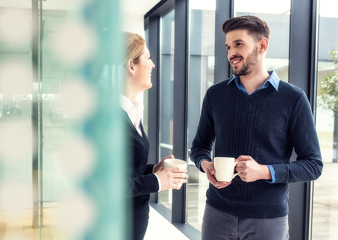Gespr&auml;chsituation mit Kaffetasse auf dem Flur eines Unternehmens