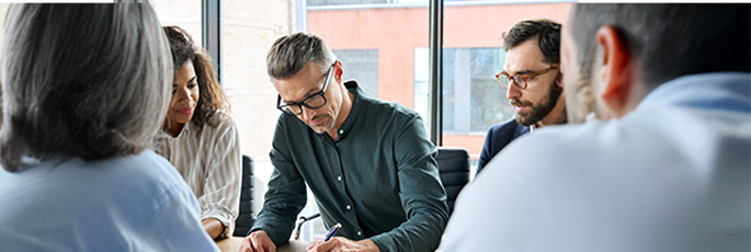 Team von Gesch&auml;ftsleuten arbeitet gemeinsam an einem Tisch &ndash; Zusammenarbeit und Vertragsfindung.