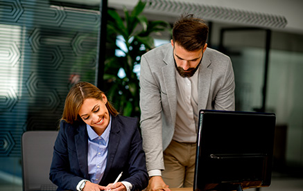 Kollege unterst&uuml;tzt Kollegin am Arbeitsplatz &ndash; gemeinsames Arbeiten an Unterlagen.
