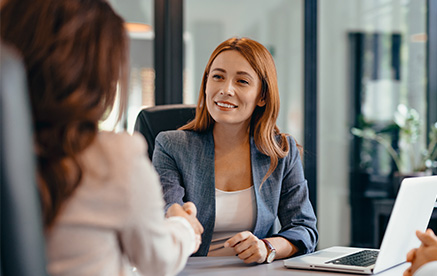 Gesch&auml;ftsfrau im Meeting gibt einer Kollegin die Hand &ndash; Vertrauen und Partnerschaft.